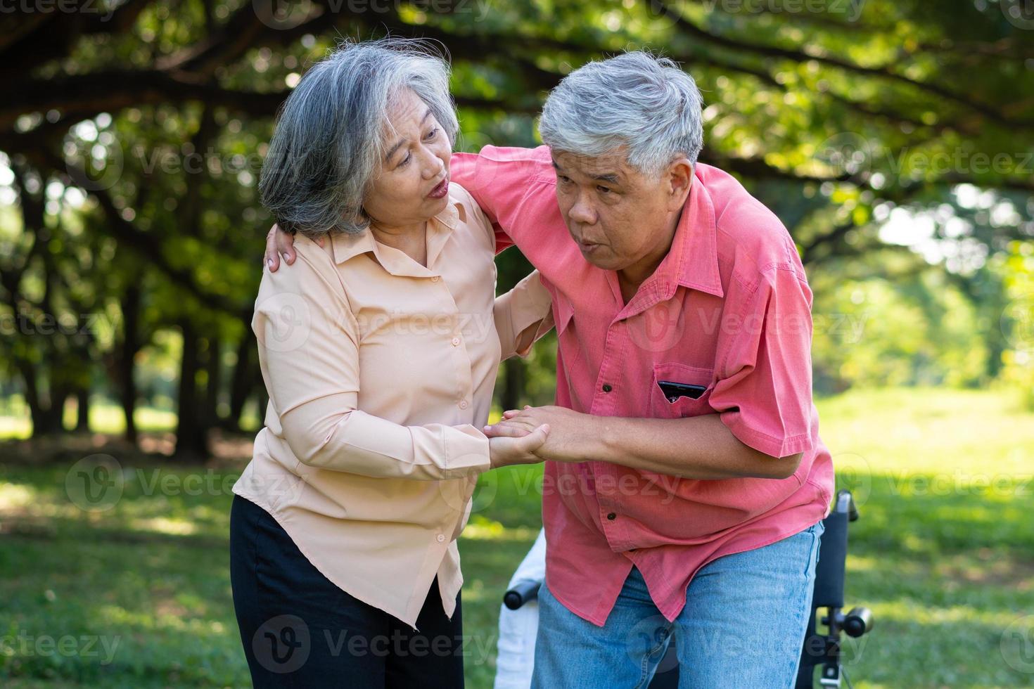 Asian senior man falling down on lying floor at park after Stumbled  and Crying in pain and him wife came to help support. Concept of old elderly insurance and health care photo