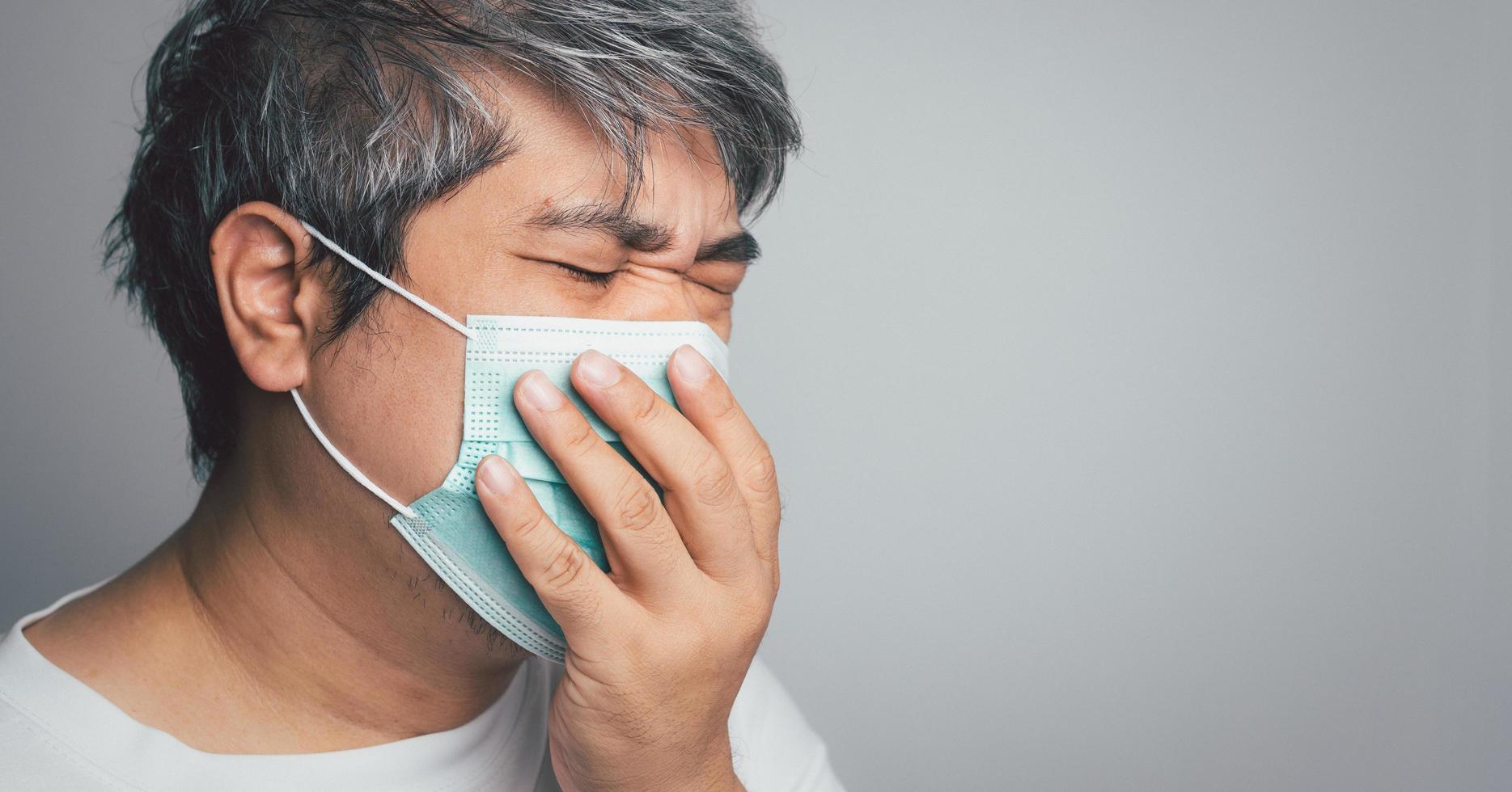 hombre asiático enfermo con una mascarilla médica y tosiendo y cubriendo su boca con mi mano. concepto de protección coronavirus pandémico y enfermedad respiratoria foto