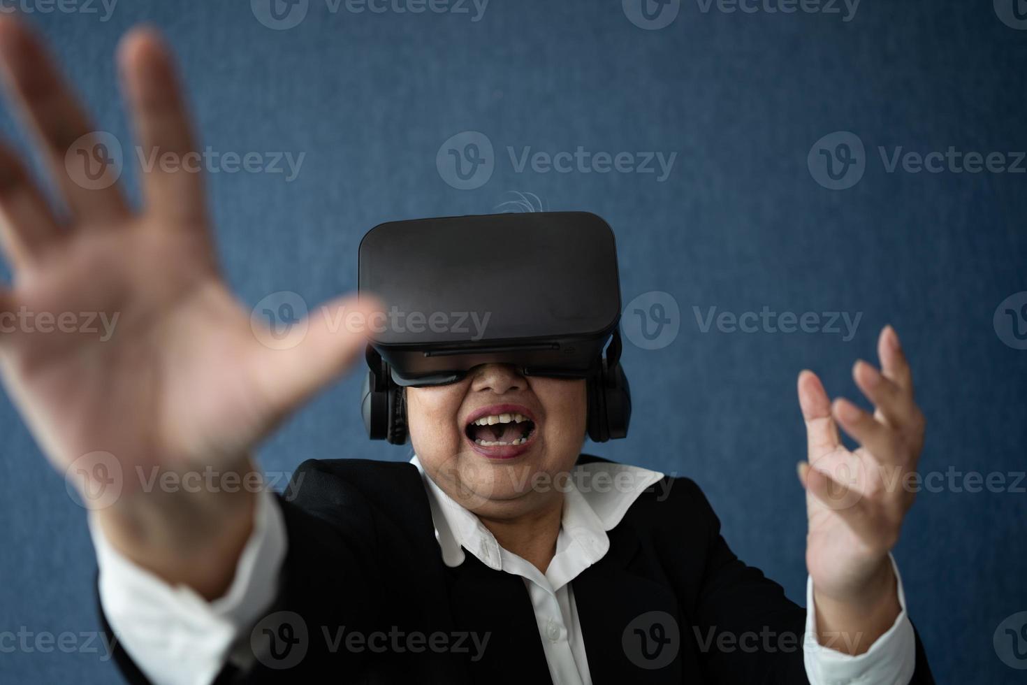 Senior Business woman wearing smart virtual glassest for Video conference, VR  headset glasses technology in modern offices and posing finger pointing and touching. Metaverse concept. photo