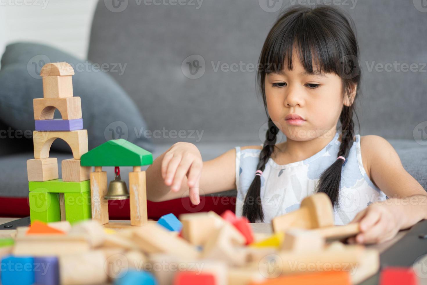 linda niña asiática jugando con coloridos bloques de juguete, los niños juegan con juguetes educativos en el jardín de infantes o en la guardería. el juego creativo del concepto de desarrollo infantil, niño pequeño en la guardería. foto