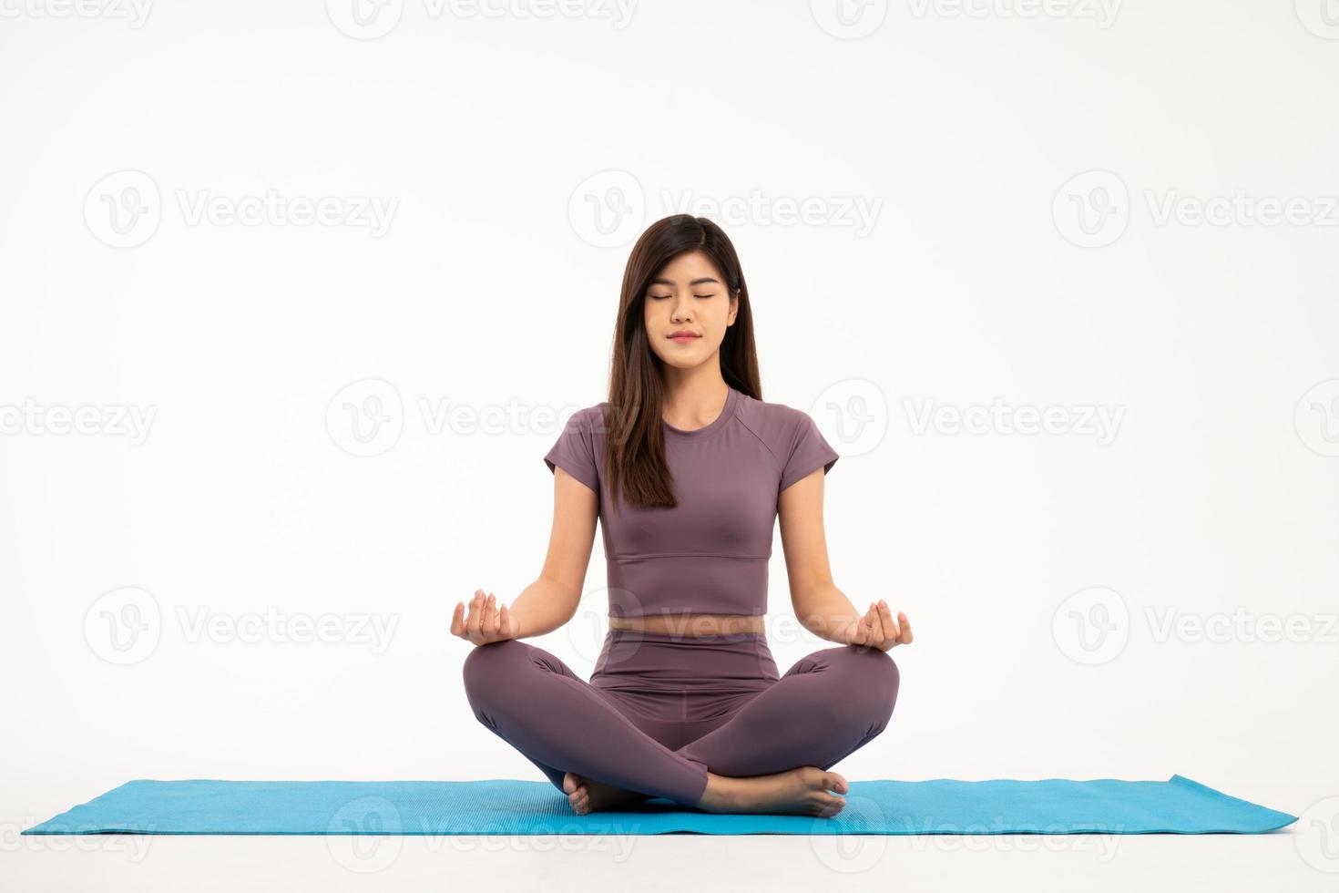 asiático deportivo y sano joven mujer haciendo yoga práctica y meditación en yoga almohadillas aislado en blanco antecedentes. concepto de sano vida foto