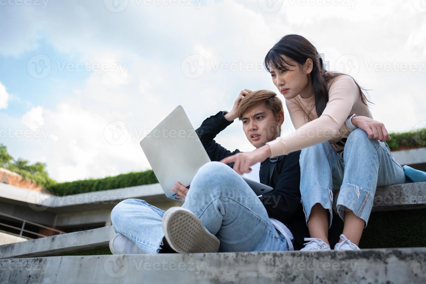 Asian students sitting on steps and use computer laptops to discuss before exams, Student lifestyle at university. Group of student do a project together photo