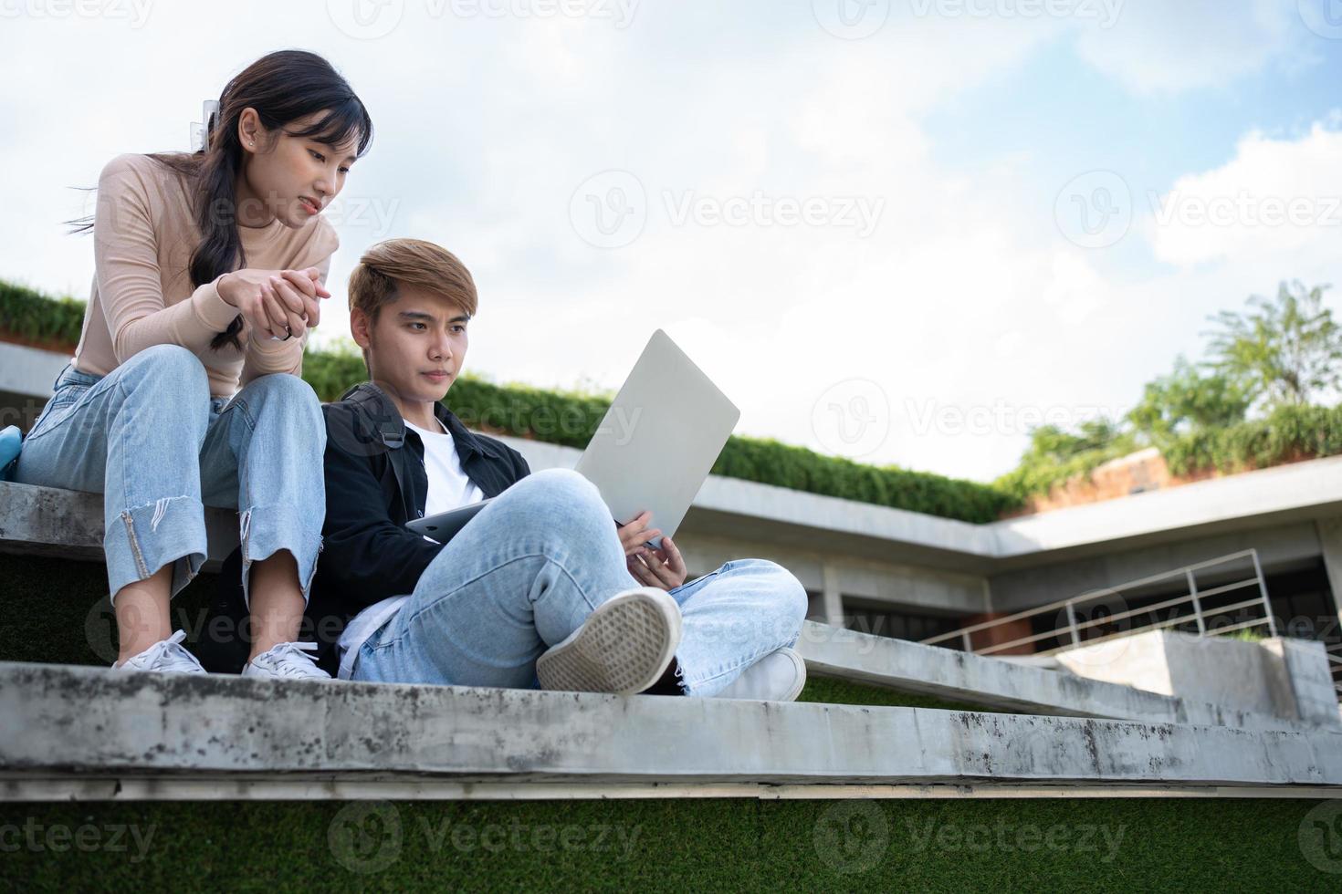 Asian students sitting on steps and use computer laptops to discuss before exams, Student lifestyle at university. Group of student do a project together photo