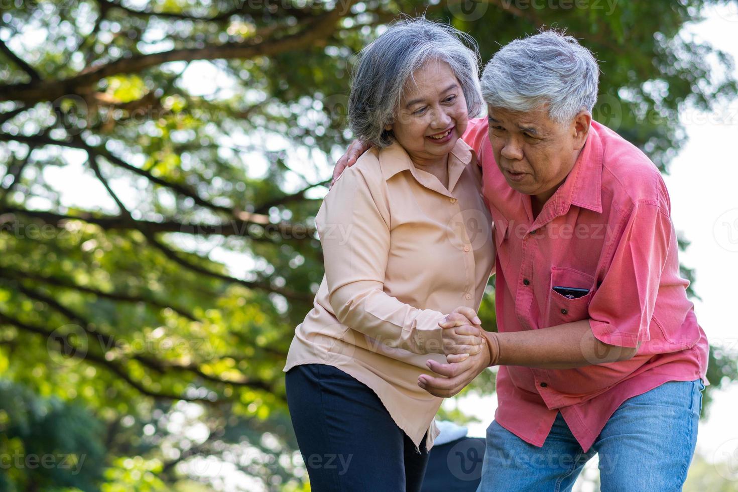 Asian senior man falling down on lying floor at park after Stumbled  and Crying in pain and him wife came to help support. Concept of old elderly insurance and health care photo