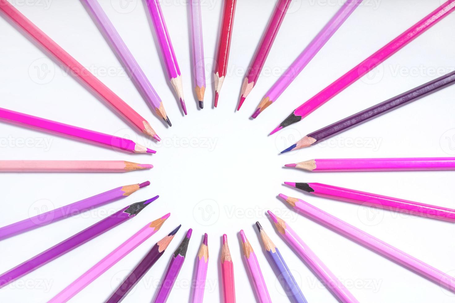 pink and purple pencils lined up in a circle on a white background. photo with round frame for copy space