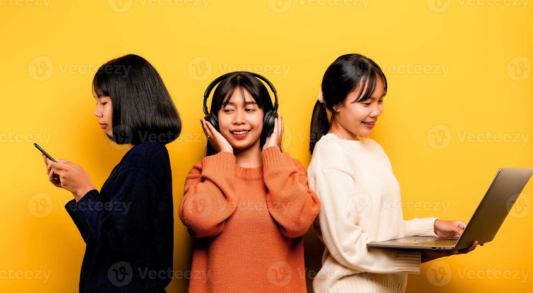 dos asiático mujer trabajando en ordenador portátil y teléfono. a el mismo hora dos de ellos fueron comunicado en línea y demostración contento sonrisas y escucha a música alrededor personas y amigos en línea comunicación foto
