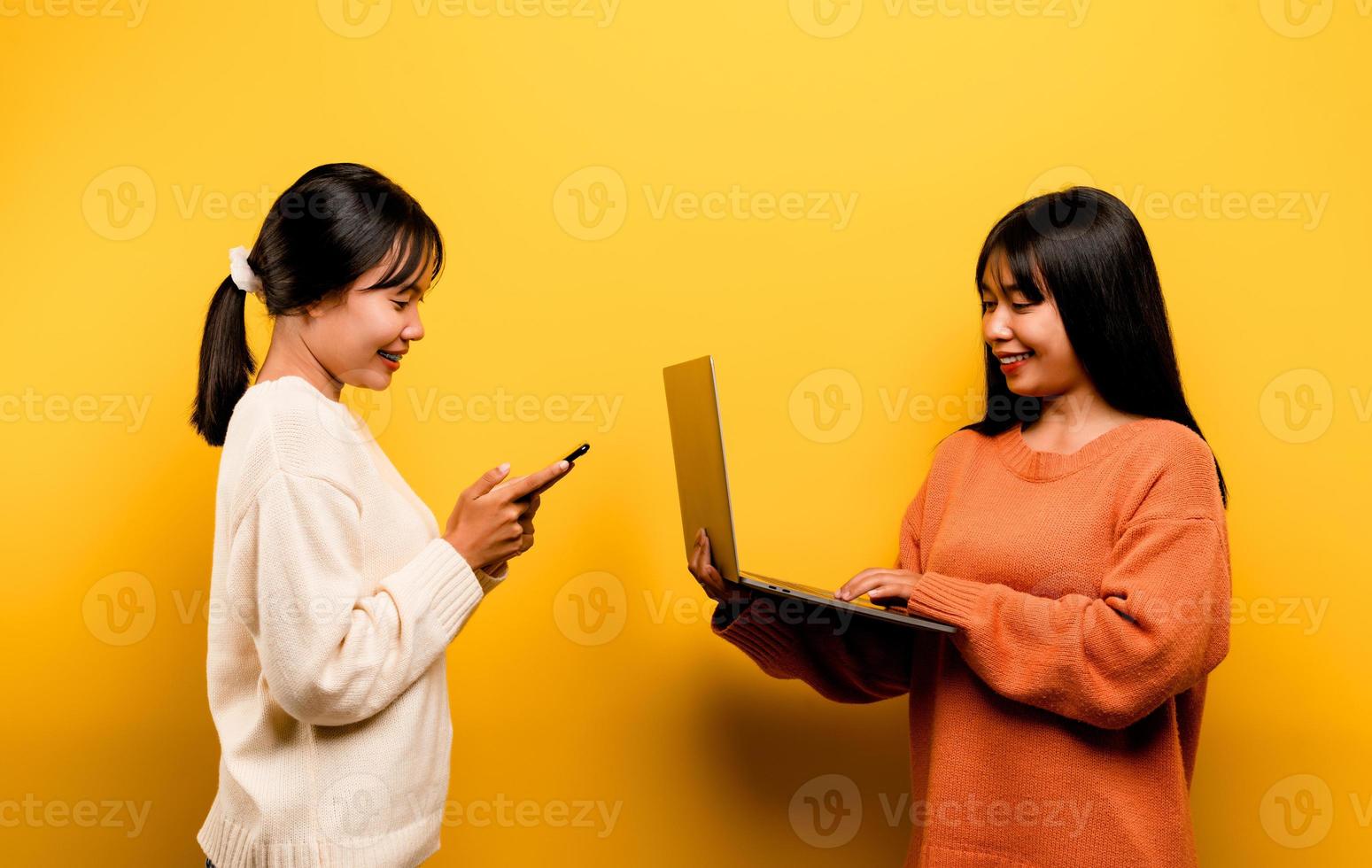 Two Asian women working on laptop and phone. at the same time Two of them were communicating online and showing happy smiles. photo