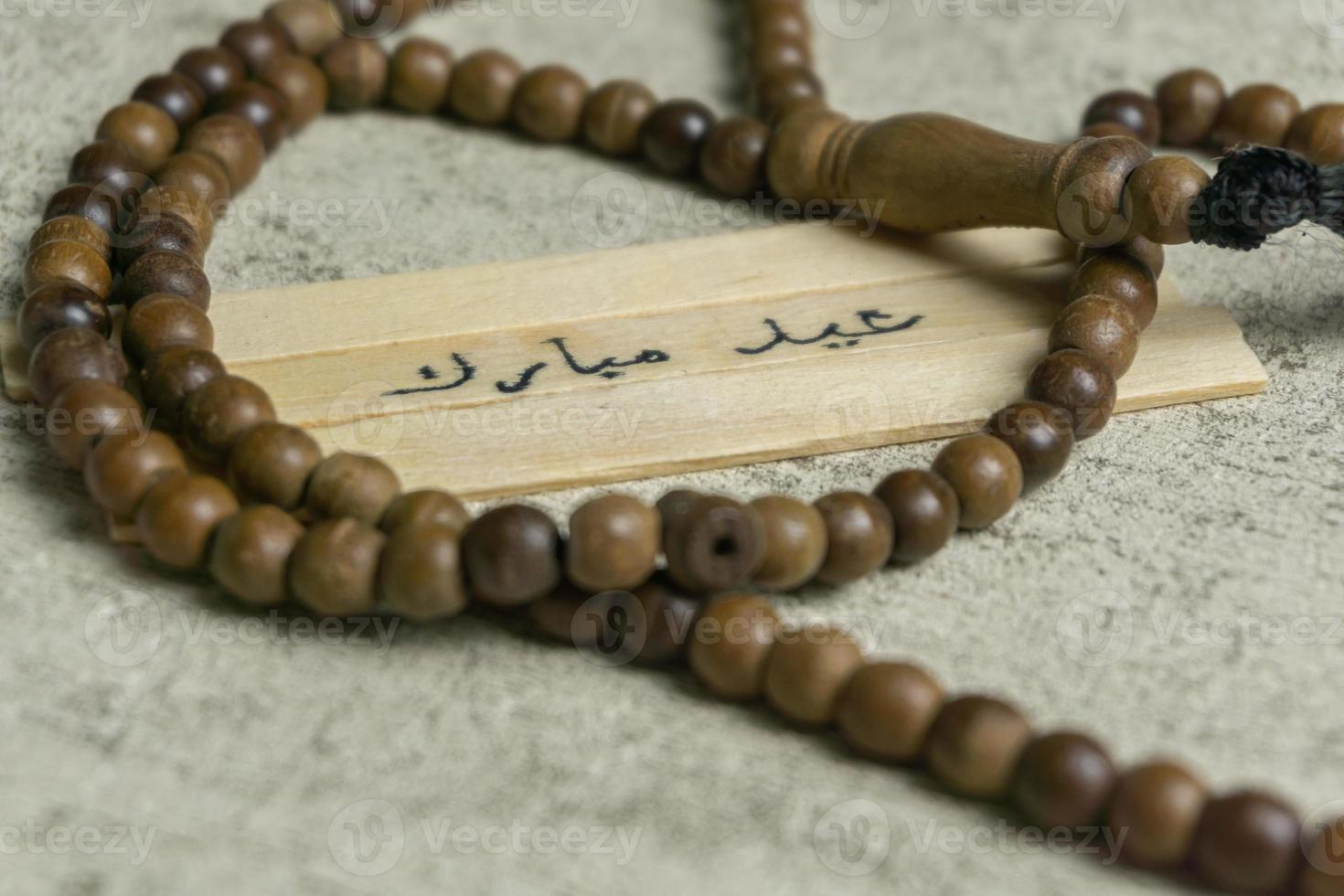 Islamic quotes. Eid Mubarak words written on wooden stick. photo