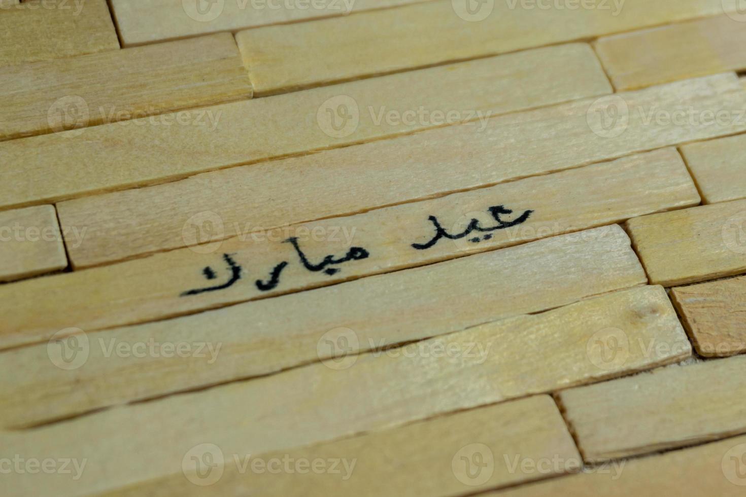 Islamic quotes. Eid Mubarak words written on wooden stick. photo