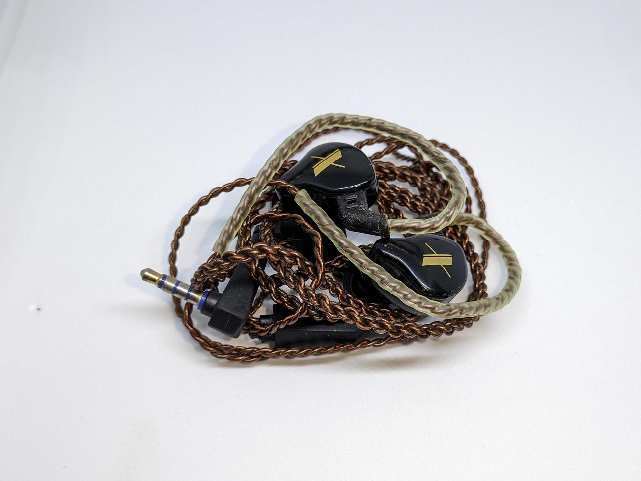 A black in ear monitor or IEM with brown cable and white background photo