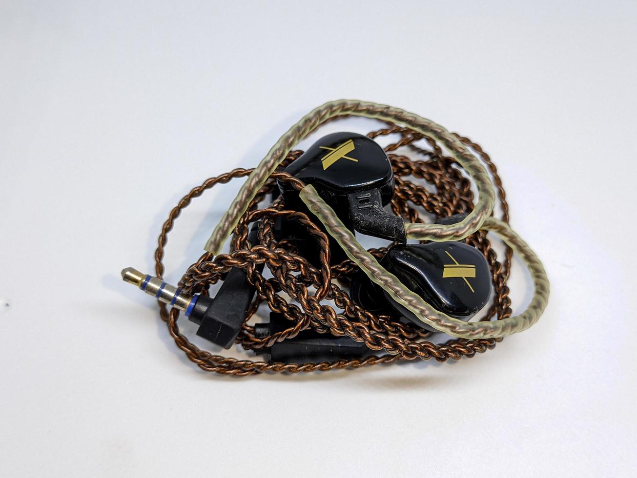 A black in ear monitor or IEM with brown cable and white background photo