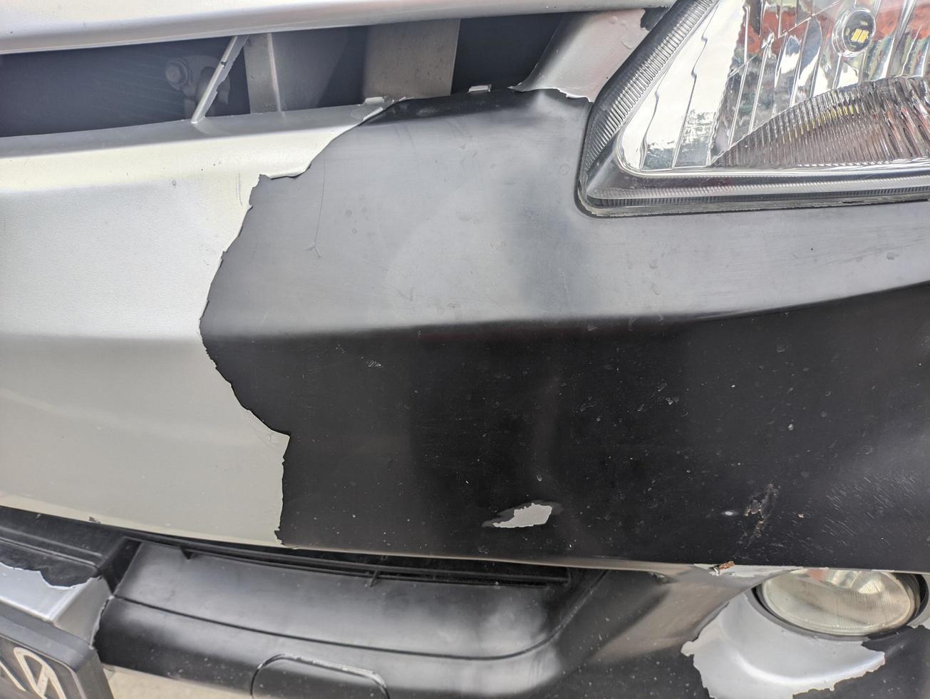 A car front bumper with peeling white paint photo