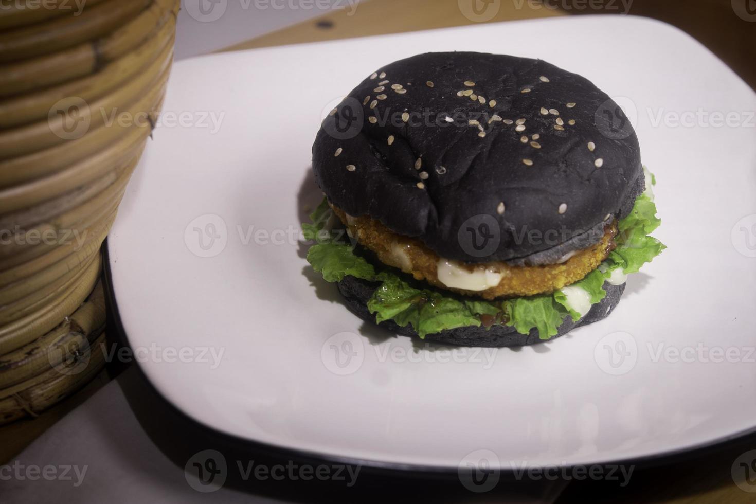 Close up photo of the opened black burger on a white plate is highly suitable for a fast food menu
