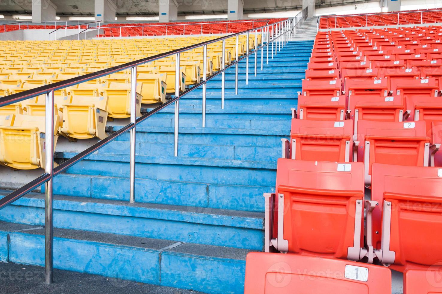 Empty orange and yellow seats at stadium,Rows walkway of seat on a soccer stadium photo
