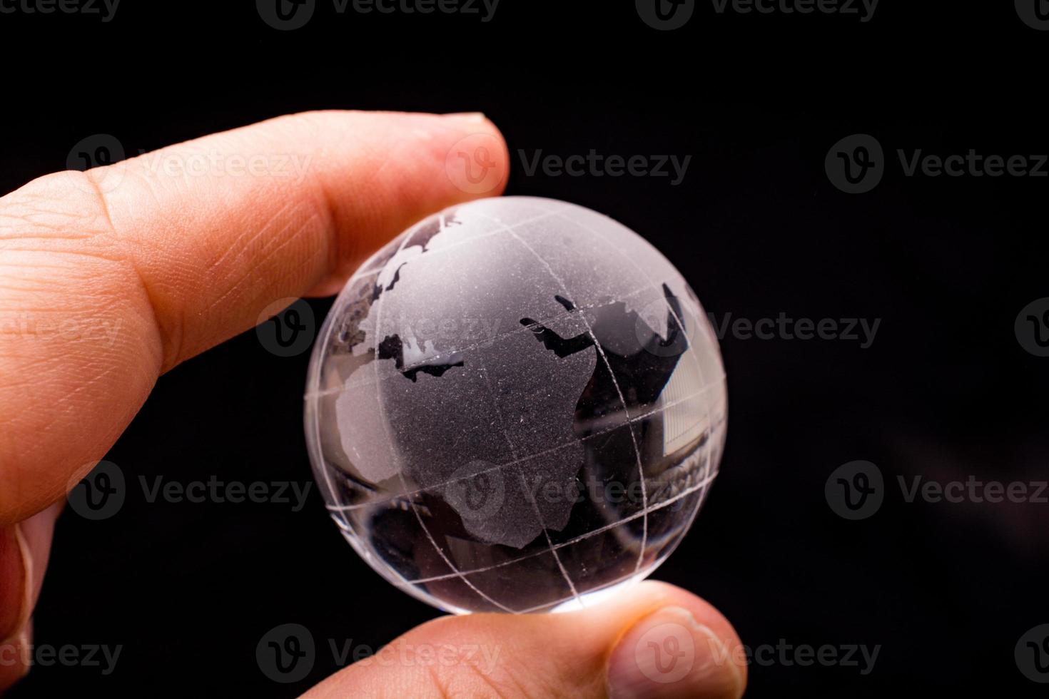 cristal de globo terráqueo en la mano. economía y negocios globales. concepto ambiental o ecológico foto