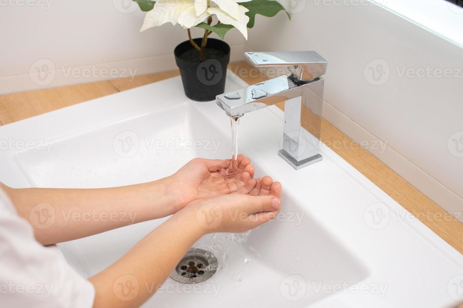 Children's hands under the water jet in the bathroom photo