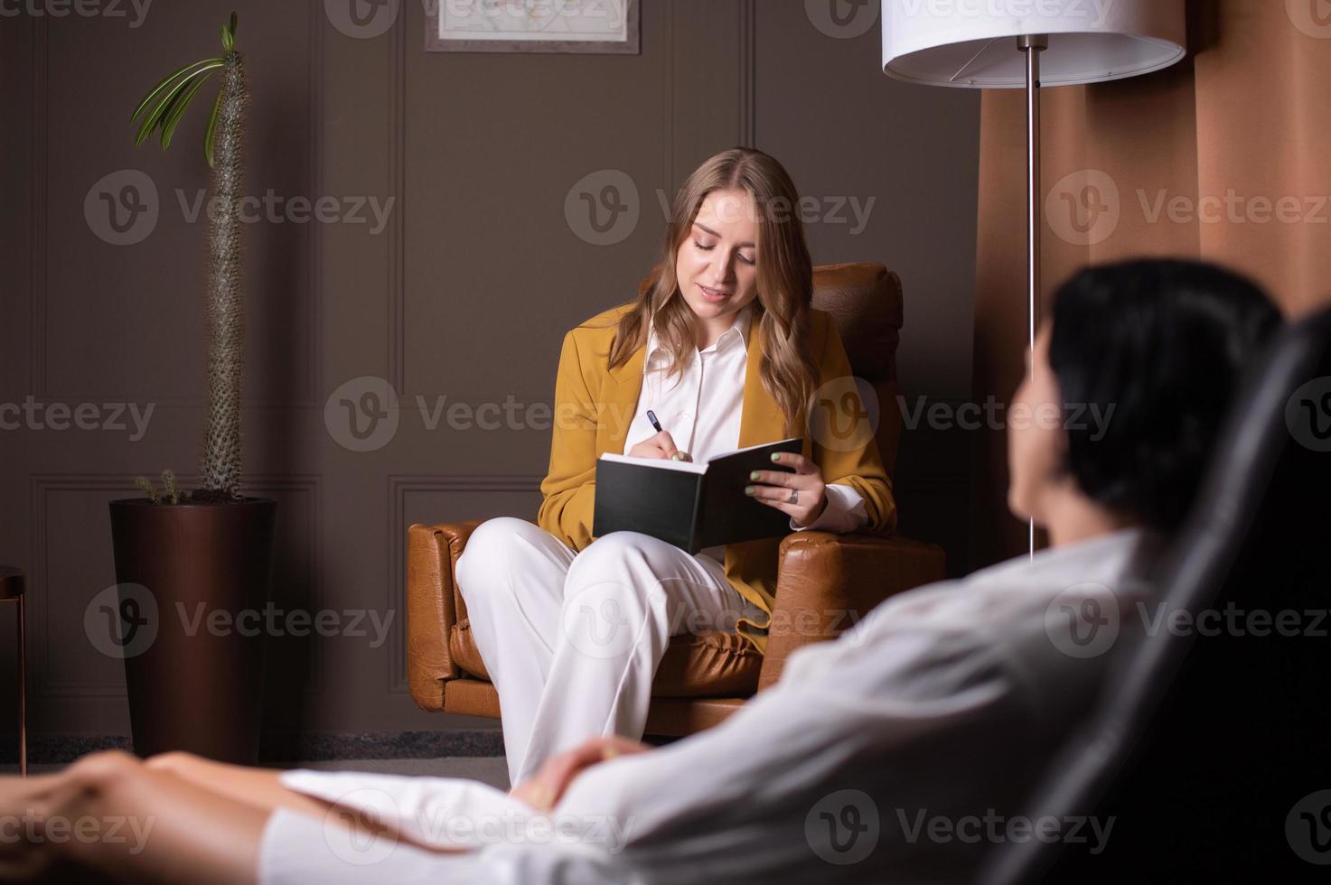 un bonito mujer hace notas acerca de el psicológico salud de un cliente foto