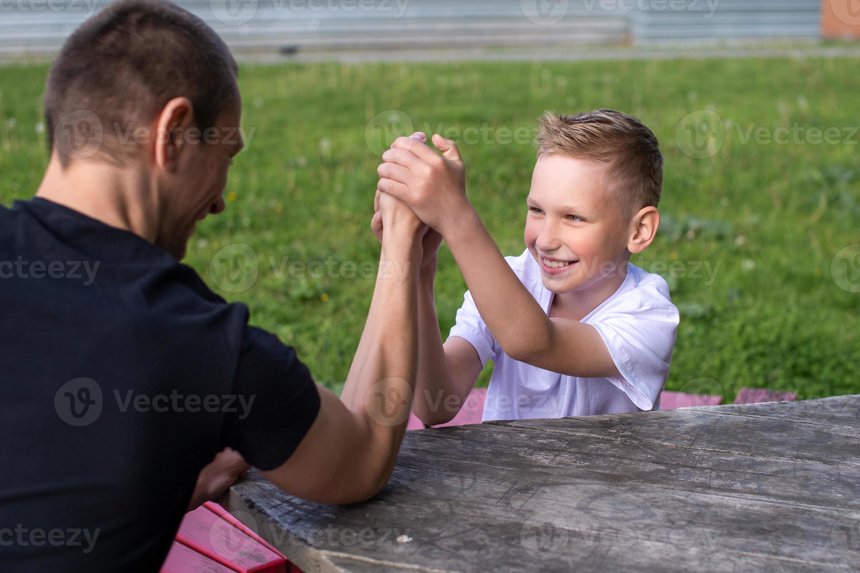 A cute child tests the strength of his hands with his dad. Powerlifting