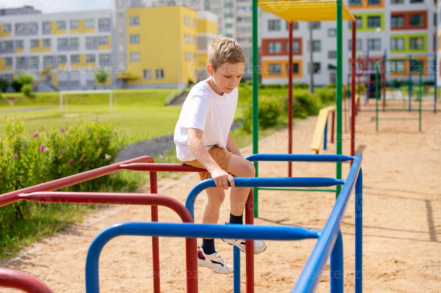 A teenage boy is engaged on horizontal bars near the school photo
