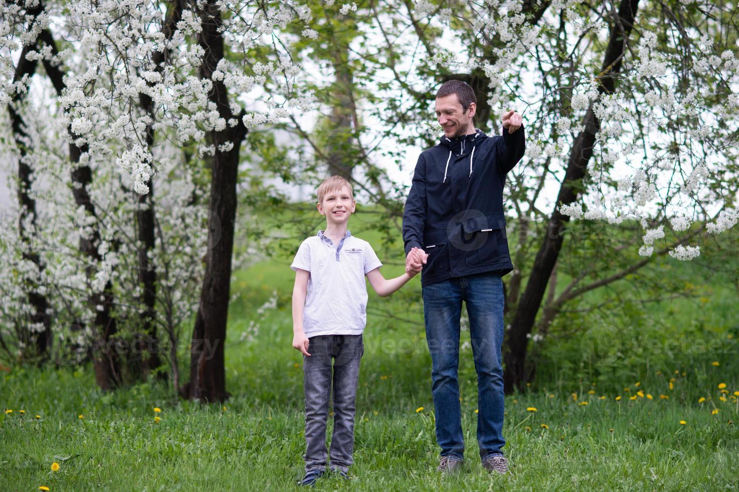 Dad walks with his son and points to the side with his hand and looks at the child photo