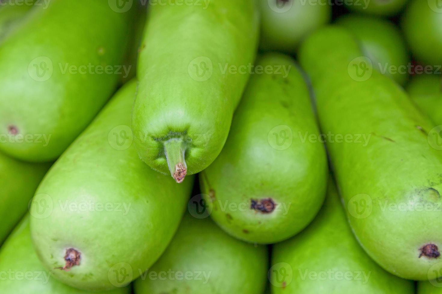 Stack of bottle gourds on a market stall photo