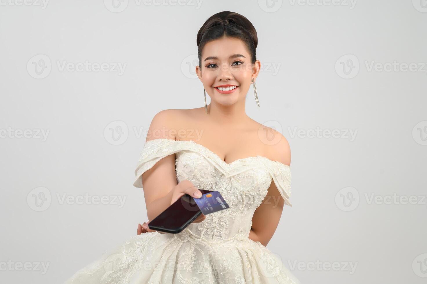 Young asian beautiful bride posting with credit card and smartphone in hand photo
