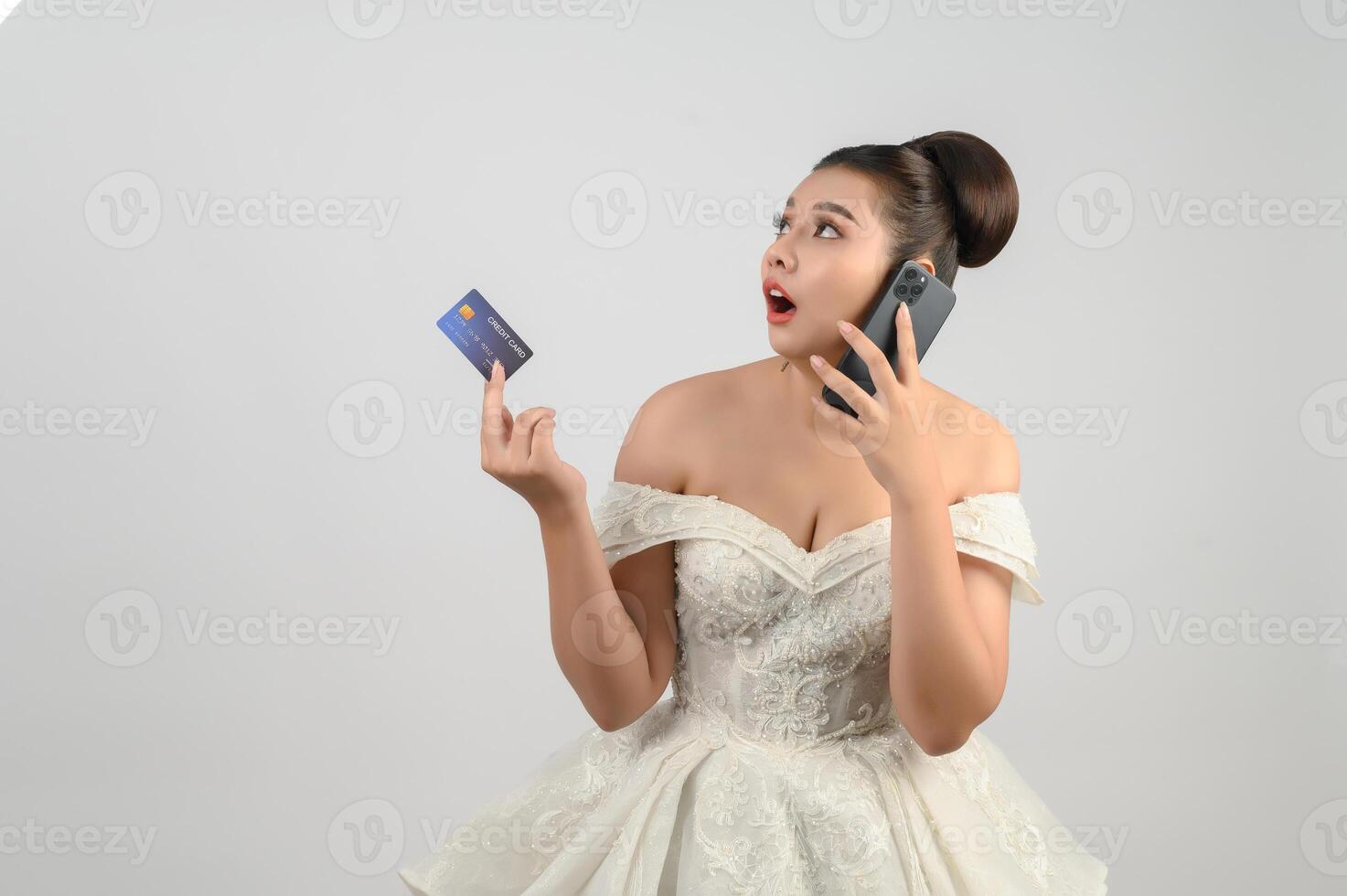 Young asian beautiful bride posting with credit card and smartphone in hand photo
