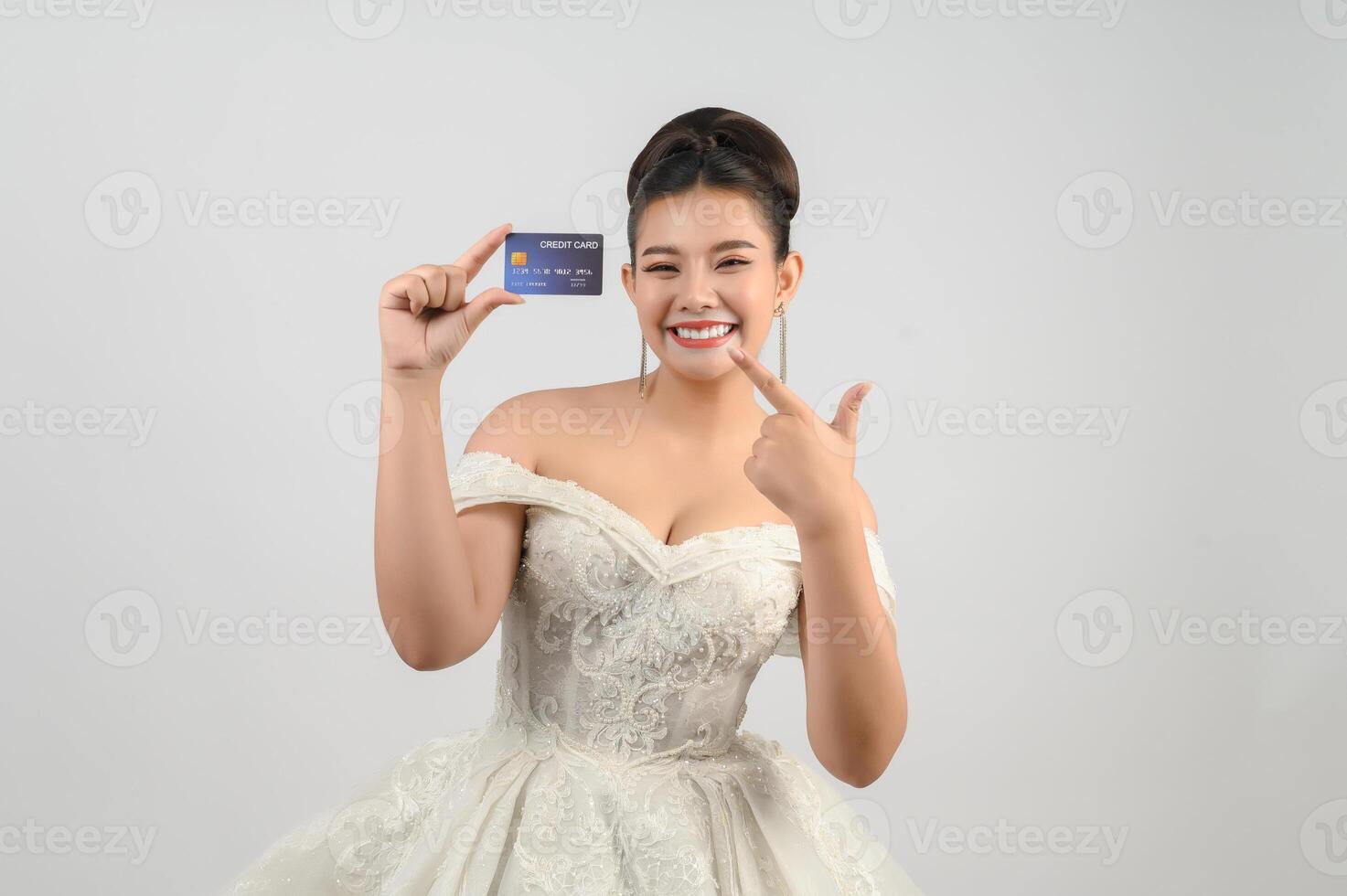 Young asian beautiful bride posting with credit card in hand photo