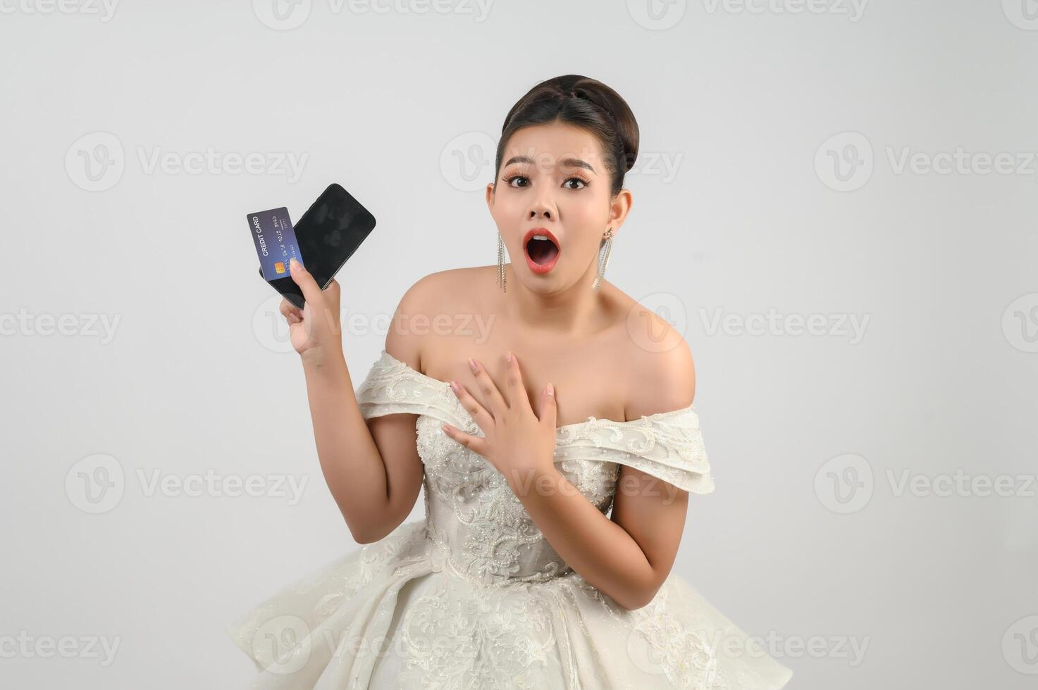 Young asian beautiful bride posting with credit card and smartphone in hand photo