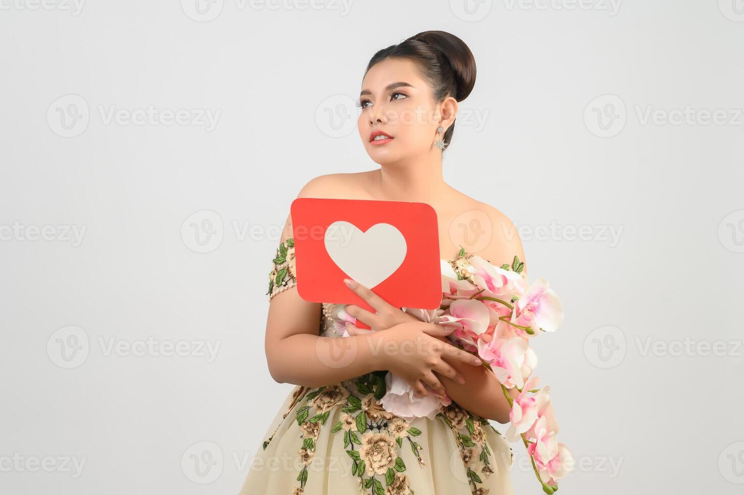 hermosa novia asiática sonriendo y posando con el signo del corazón en el fondo blanco foto