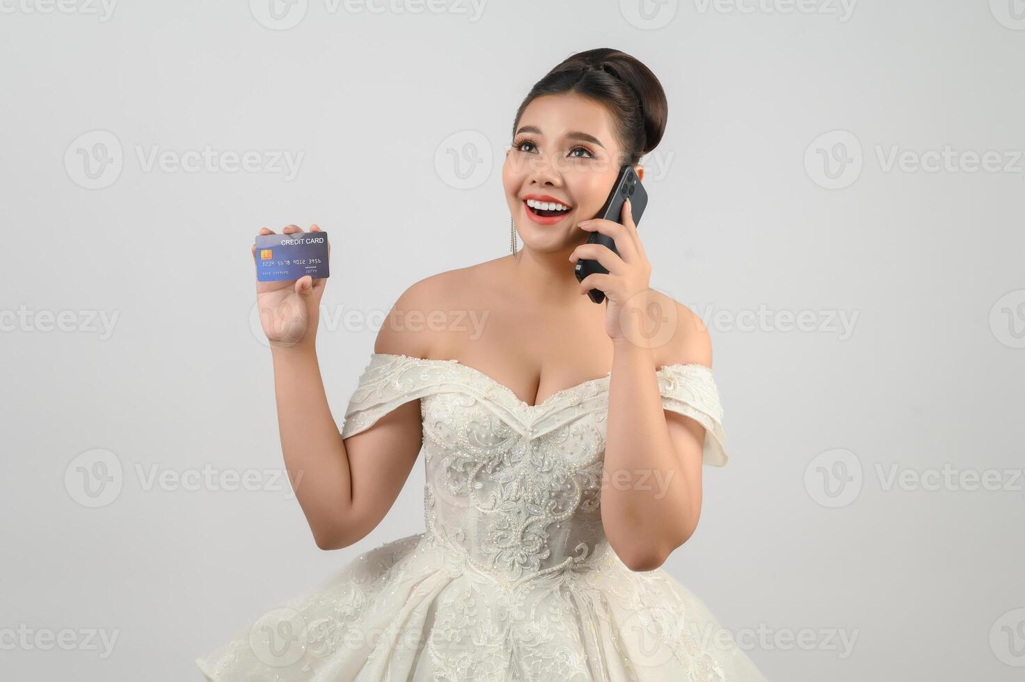 Young asian beautiful bride posting with credit card and smartphone in hand photo