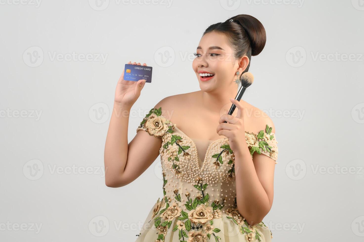 Young asian beautiful bride posting with credit card and beauty brush in hand photo