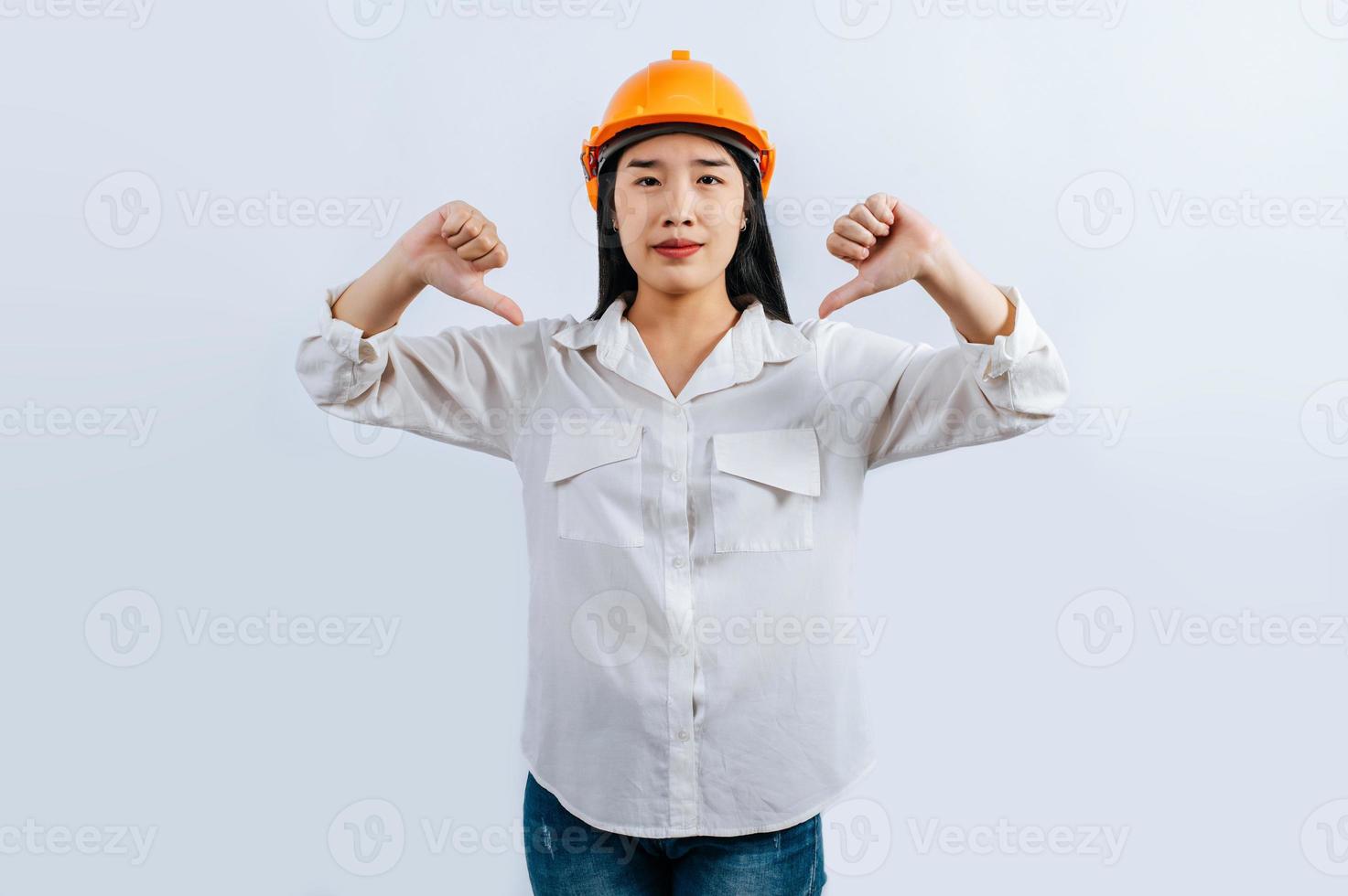 joven hembra ingeniero en casco estar con pulgar arriba postura foto