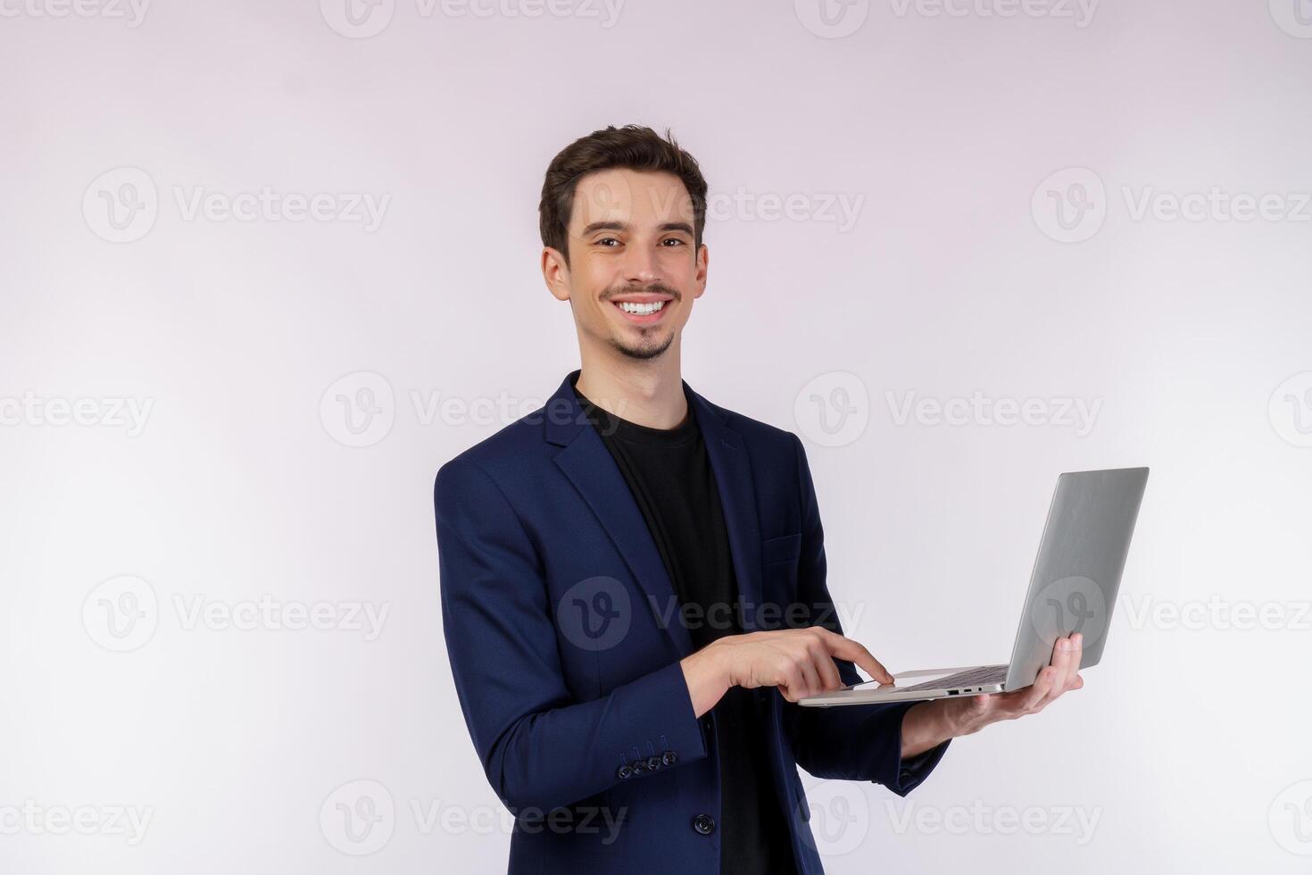 Portrait of young handsome smiling businessman holding laptop in hands, typing and browsing web pages isolated on white background photo