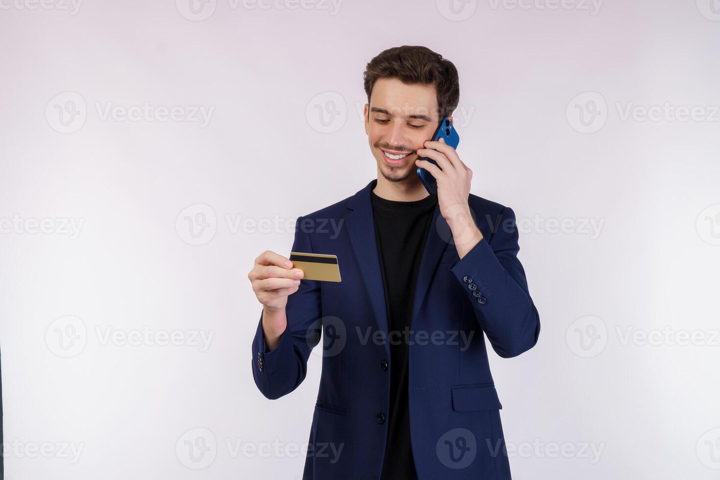 Portrait of happy handsome businessman talking by mobile phone and holding credit card isolated over white background photo