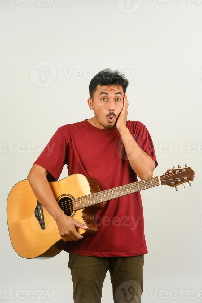 retrato de un joven asiático con una camiseta roja tocando una guitarra acústica aislada de fondo blanco foto