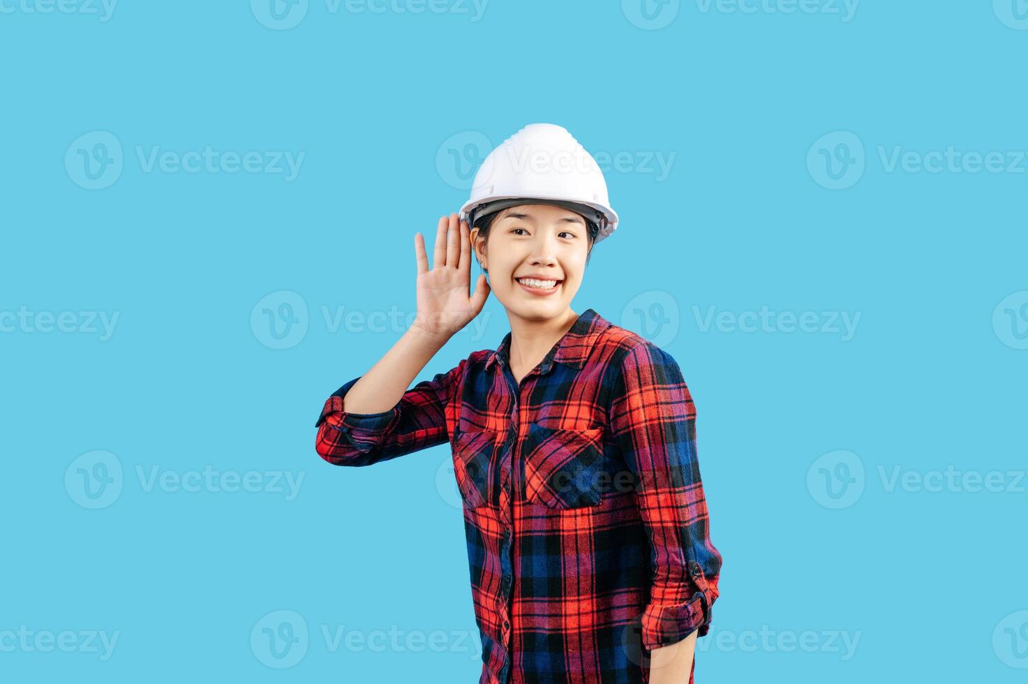 Young female engineer hand over ear to making hear gesture photo