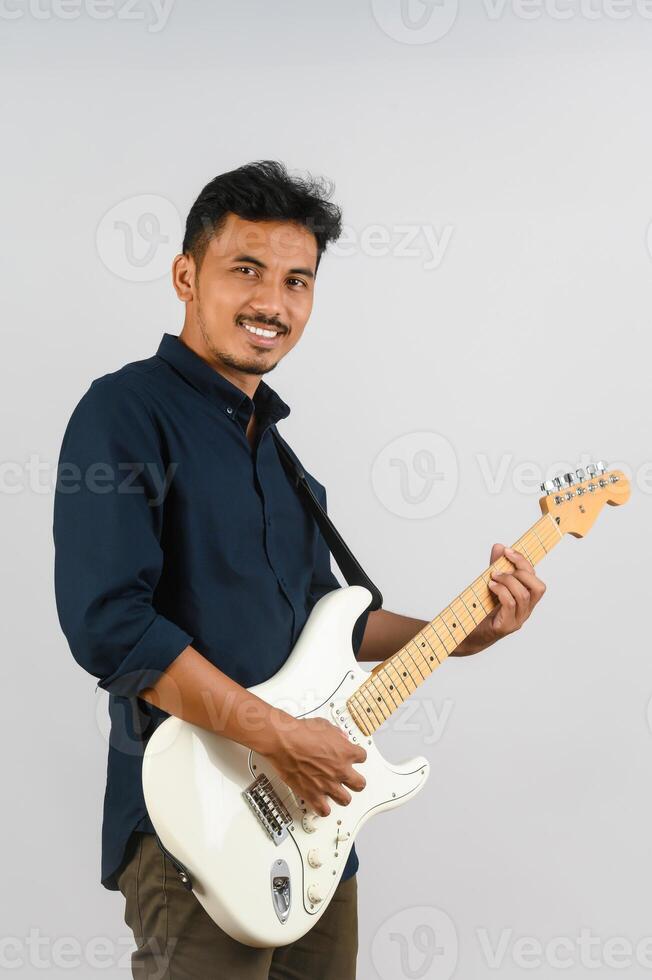 retrato de un joven asiático con camisa azul y guitarra electrónica aislado de fondo blanco foto