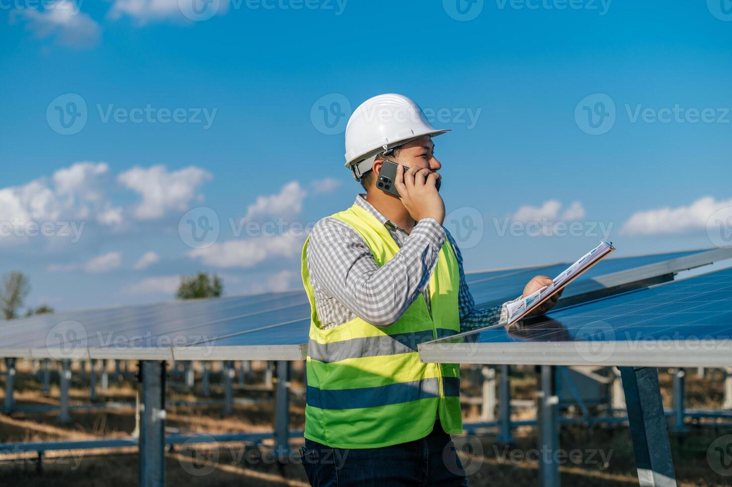 joven ingeniero hablando por teléfono inteligente mientras trabaja en una granja solar foto