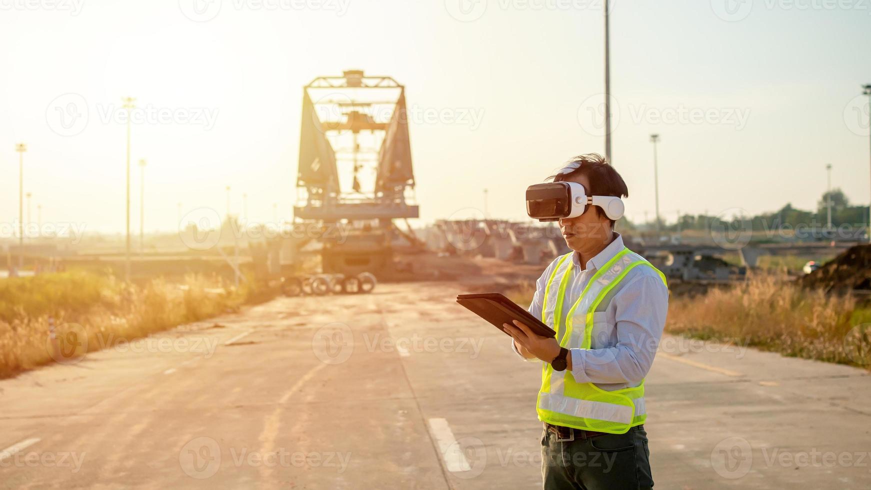 asiático ingeniero utilizando virtual realidad auriculares y tableta para inspeccionando y trabajando a construcción sitio foto