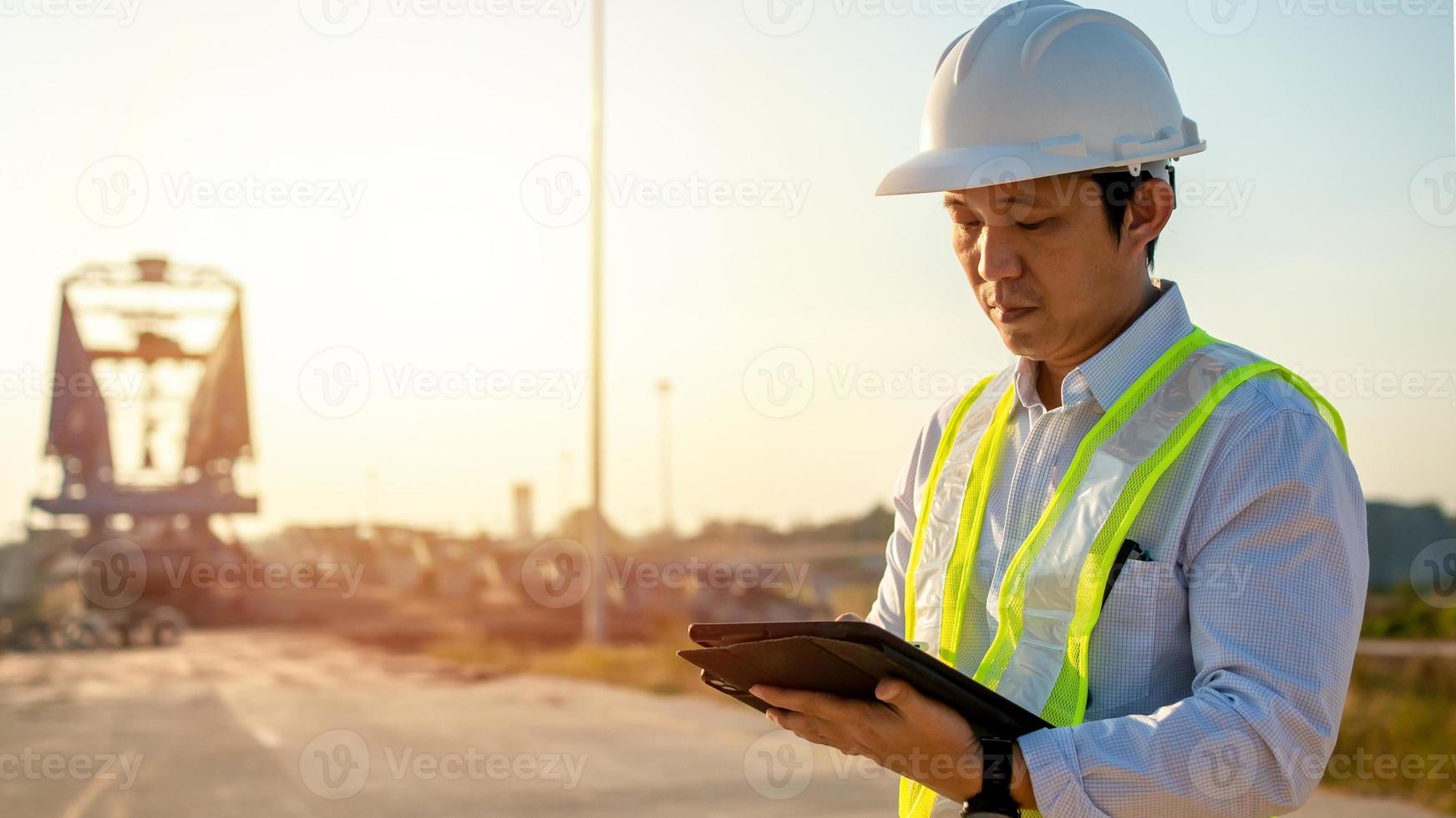 Asian engineer with hardhat using tablet pc computer inspecting and working at construction site photo
