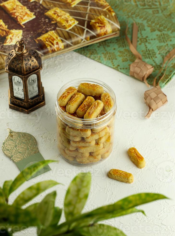 kastegel galletas en un tarro en blanco mesa. kastegel o kaasstengels es holandés influenciado indonesio queso galletas. eso por lo general servido en ramadán, eid fitr y eid adha. foto