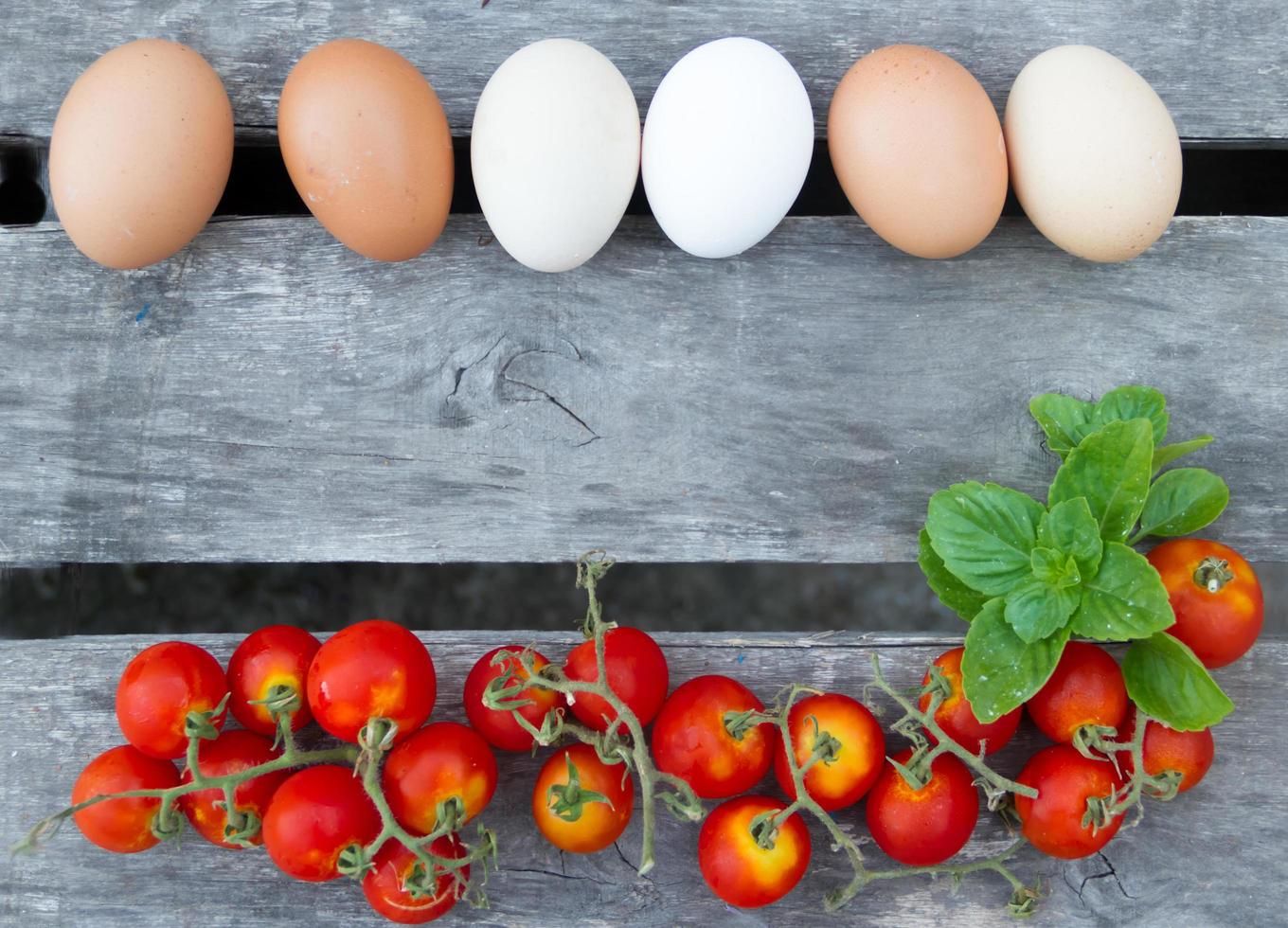edge of eggs and tomatoes on rustic wood photo