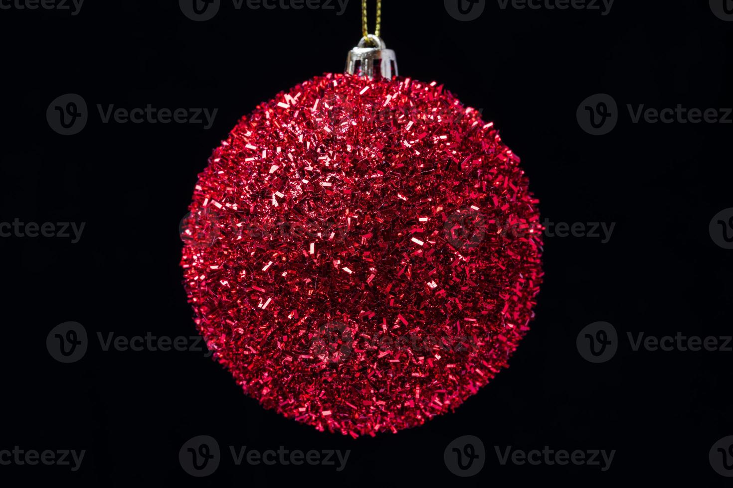 Close-up view of shiny bright red Christmas ball hanging on black background. Celebration Xmas composition for Happy New Year photo