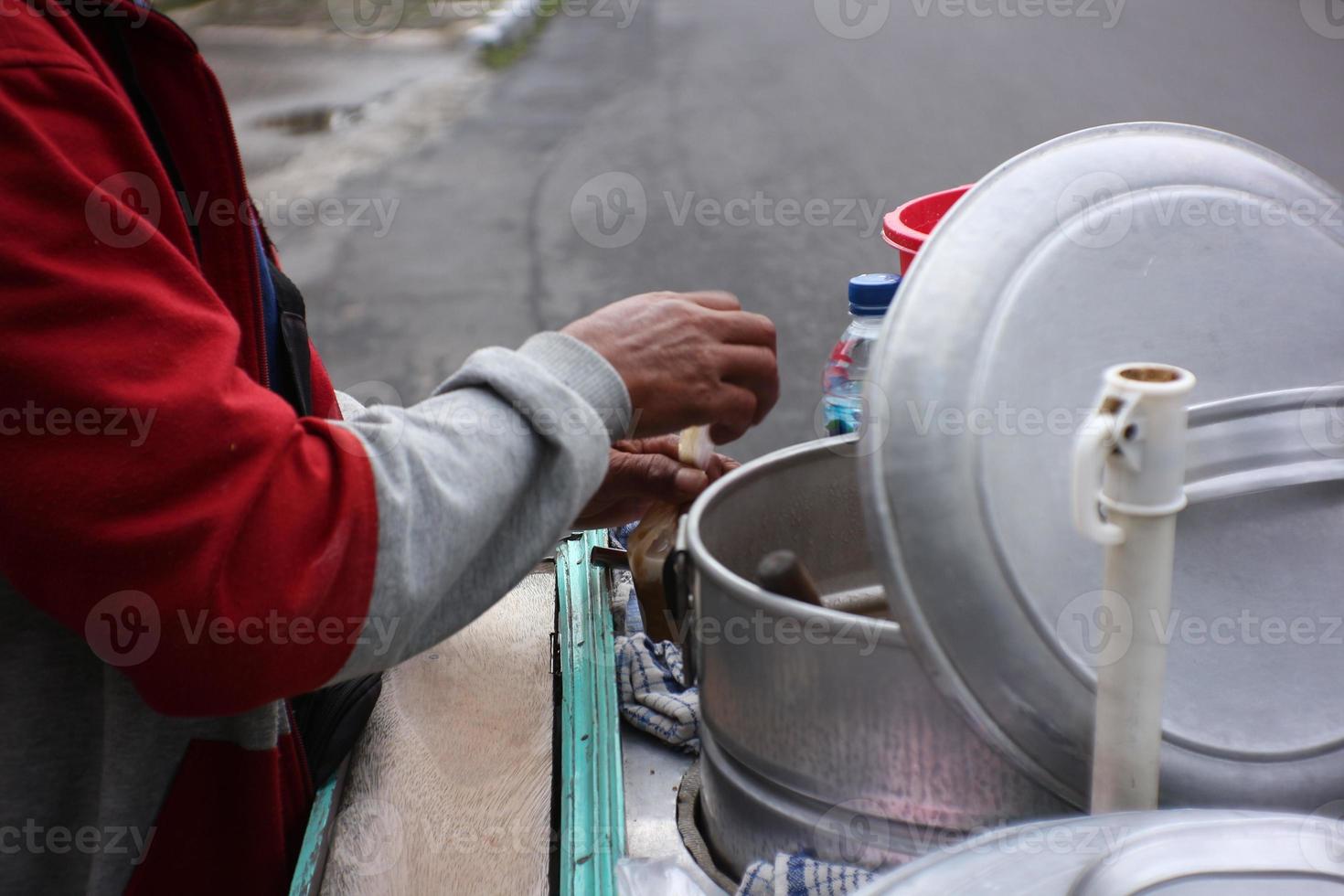 man street food seller serving the indonesian traditional green bean porridge on his silver cart photo