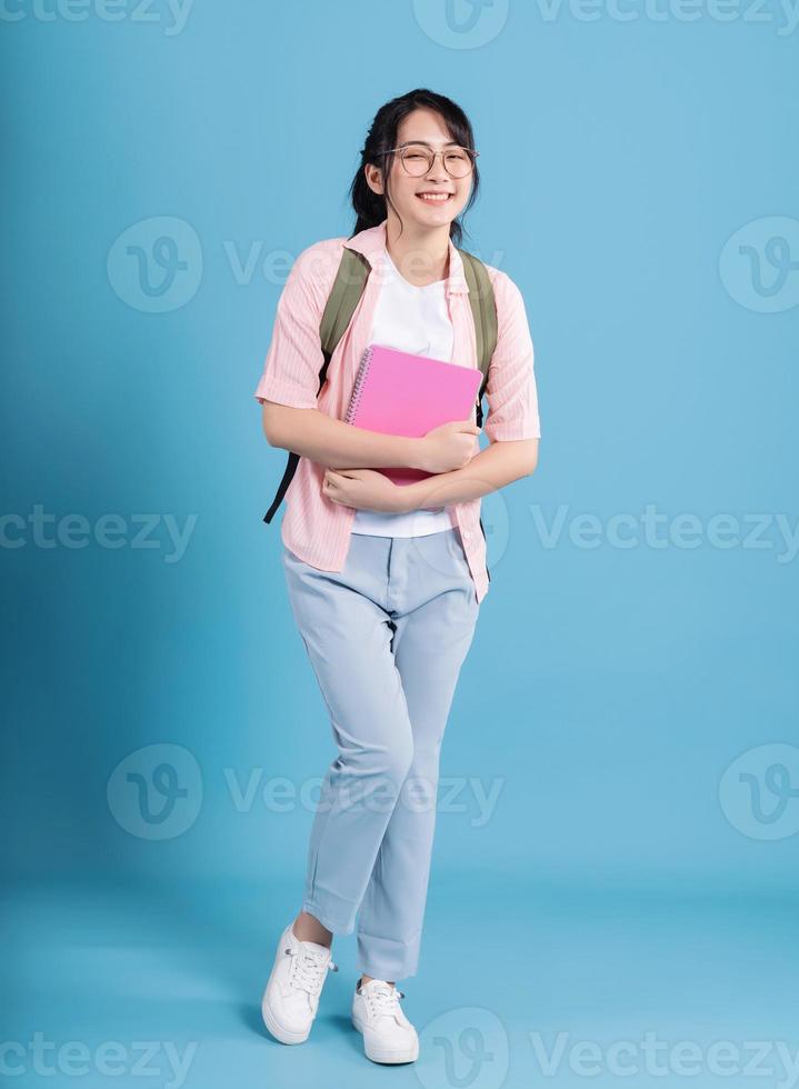 Young Asian student on blue background photo