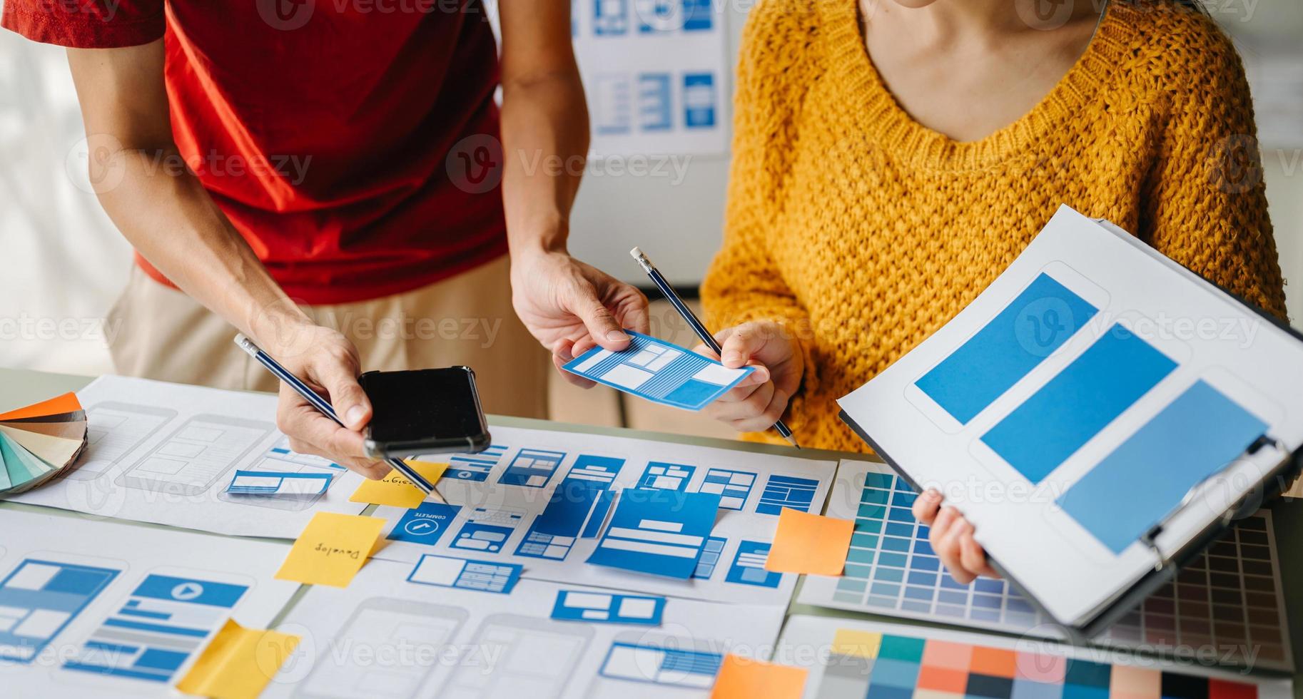 UX developer and ui designer brainstorming about mobile app interface wireframe design with customer breif and color code at office. photo