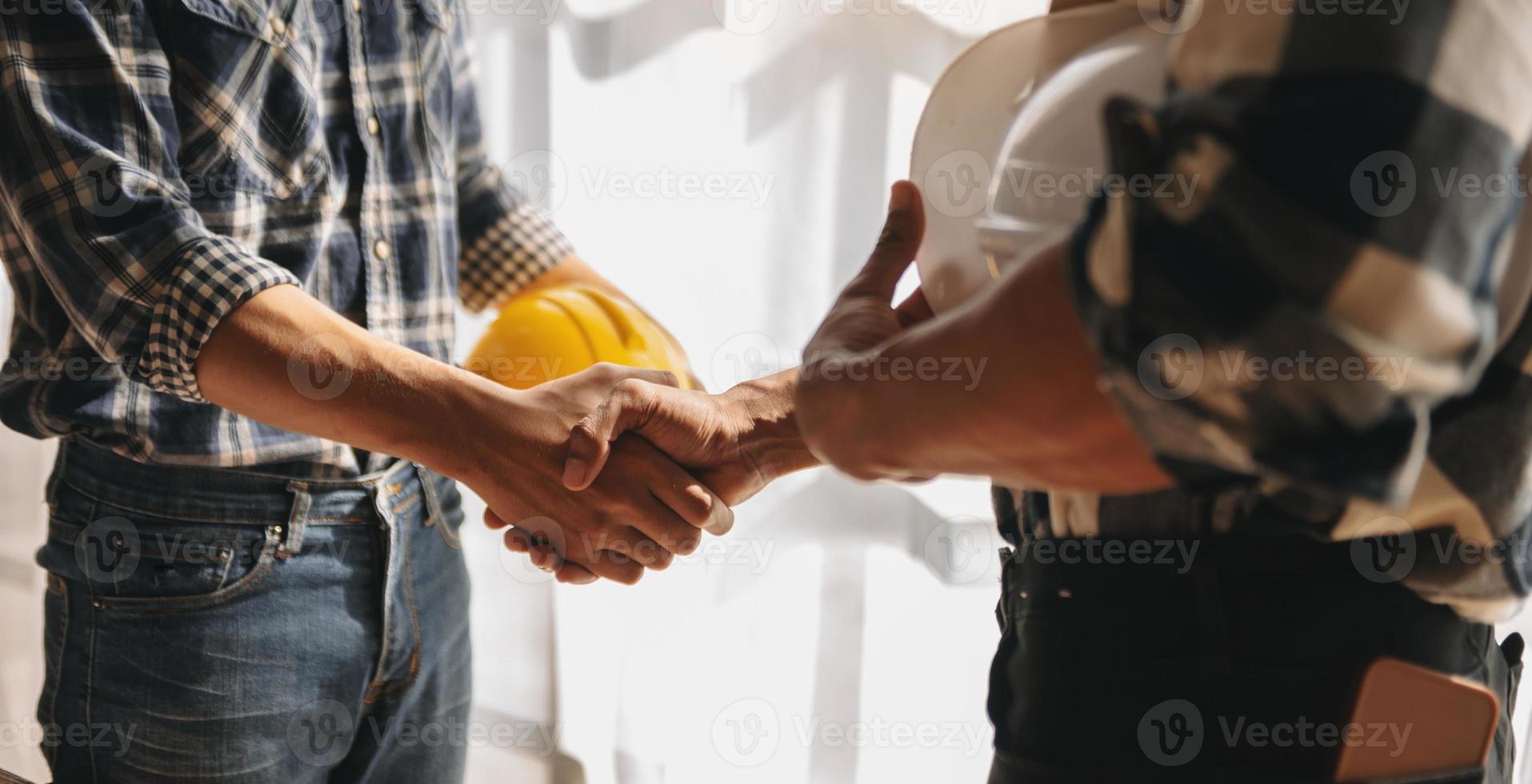 Engineer and contractor join hands after signing contract,They are having a modern building project together. photo