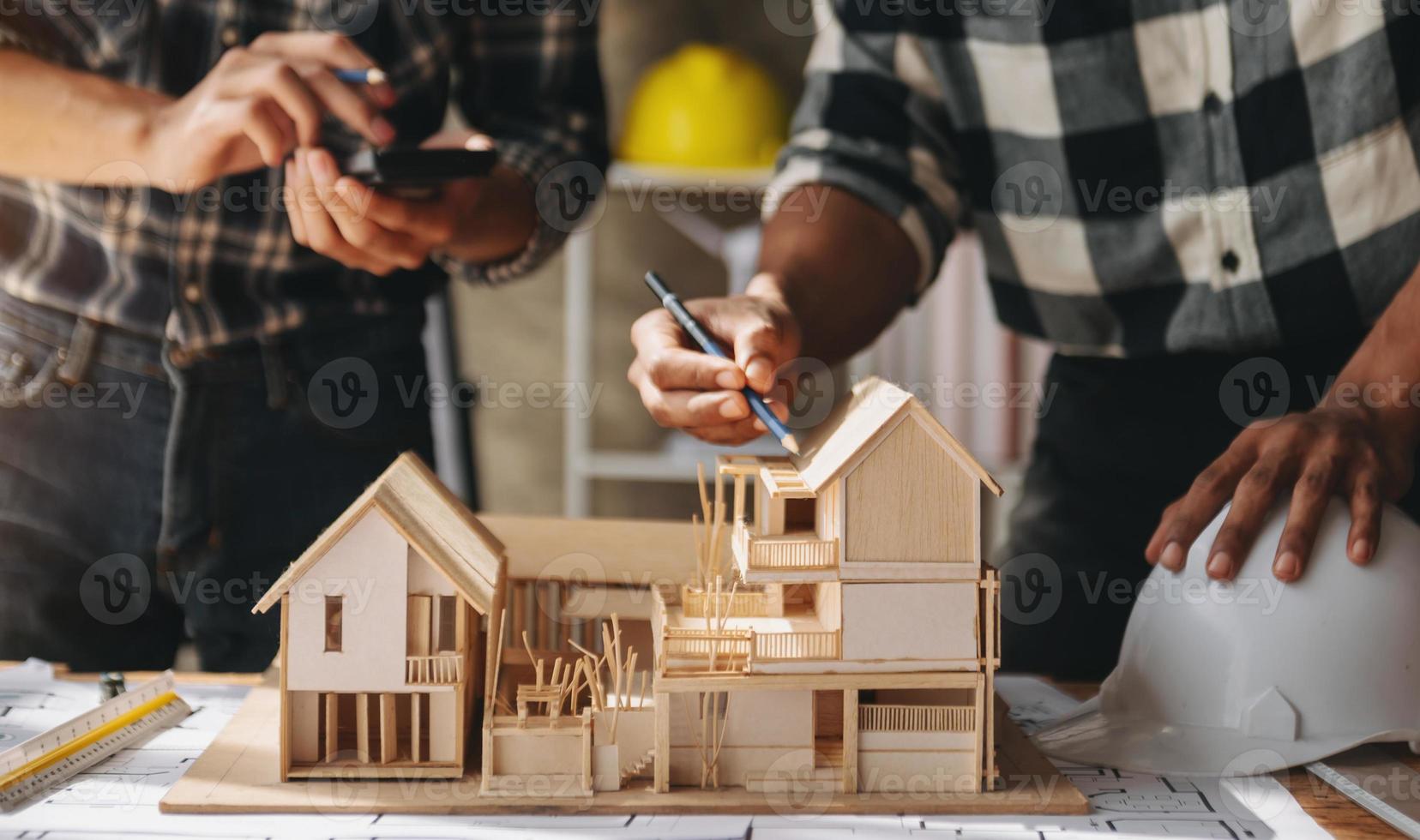 Close up shot of scale model house on table with architects. Two architects making architectural model in office together. to form a new building photo