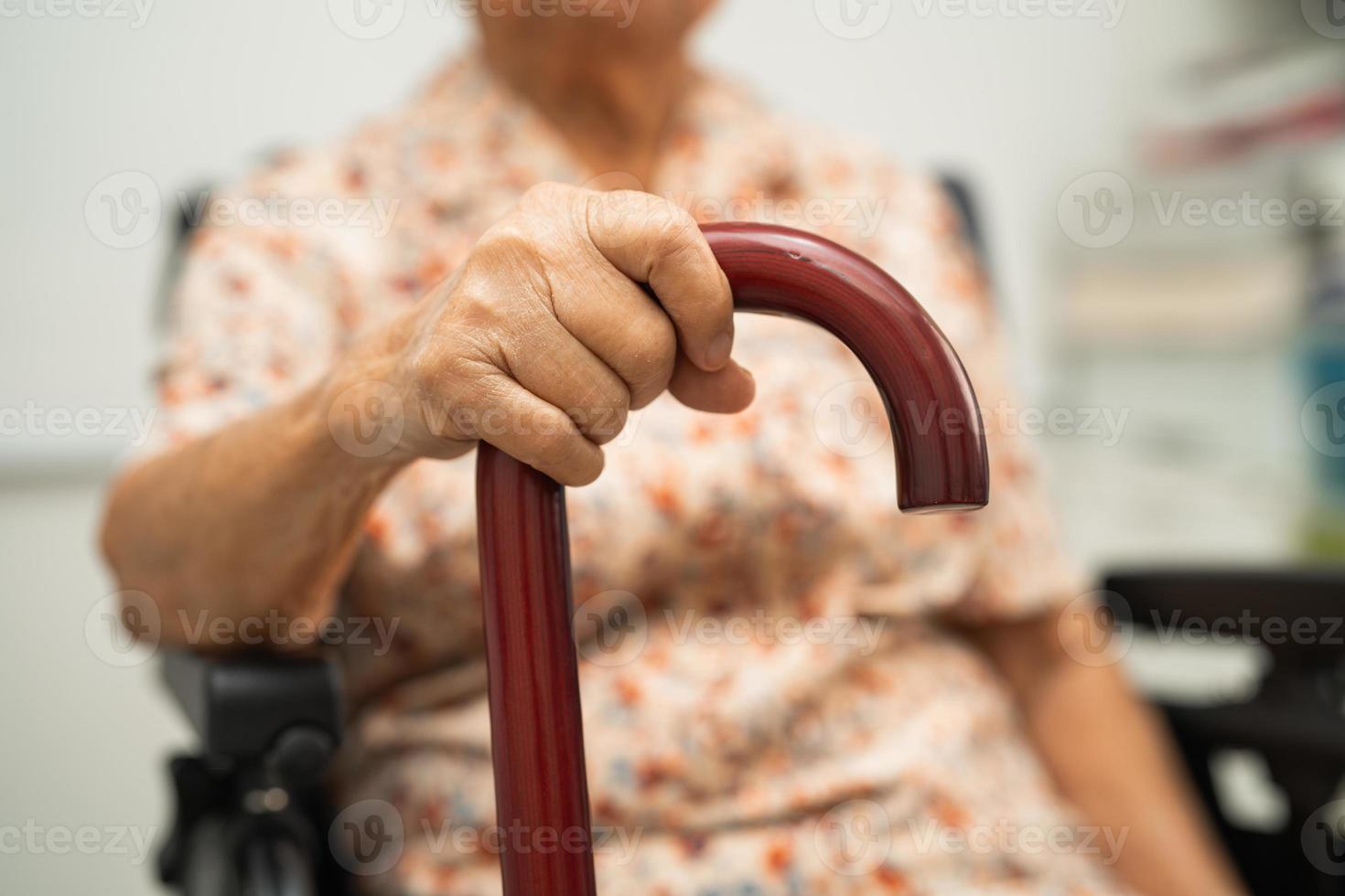 Asian elderly disability woman holding waling stick, wood cane, round handle, walking aid for help to walk. photo